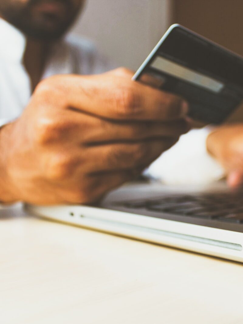 person using laptop computer holding card