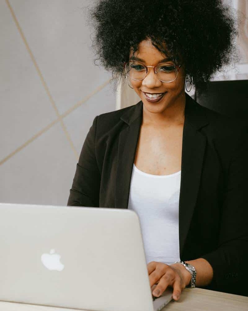 Woman In White Shirt And Black Blazer Using Silver Macbook at Zindua Coding School