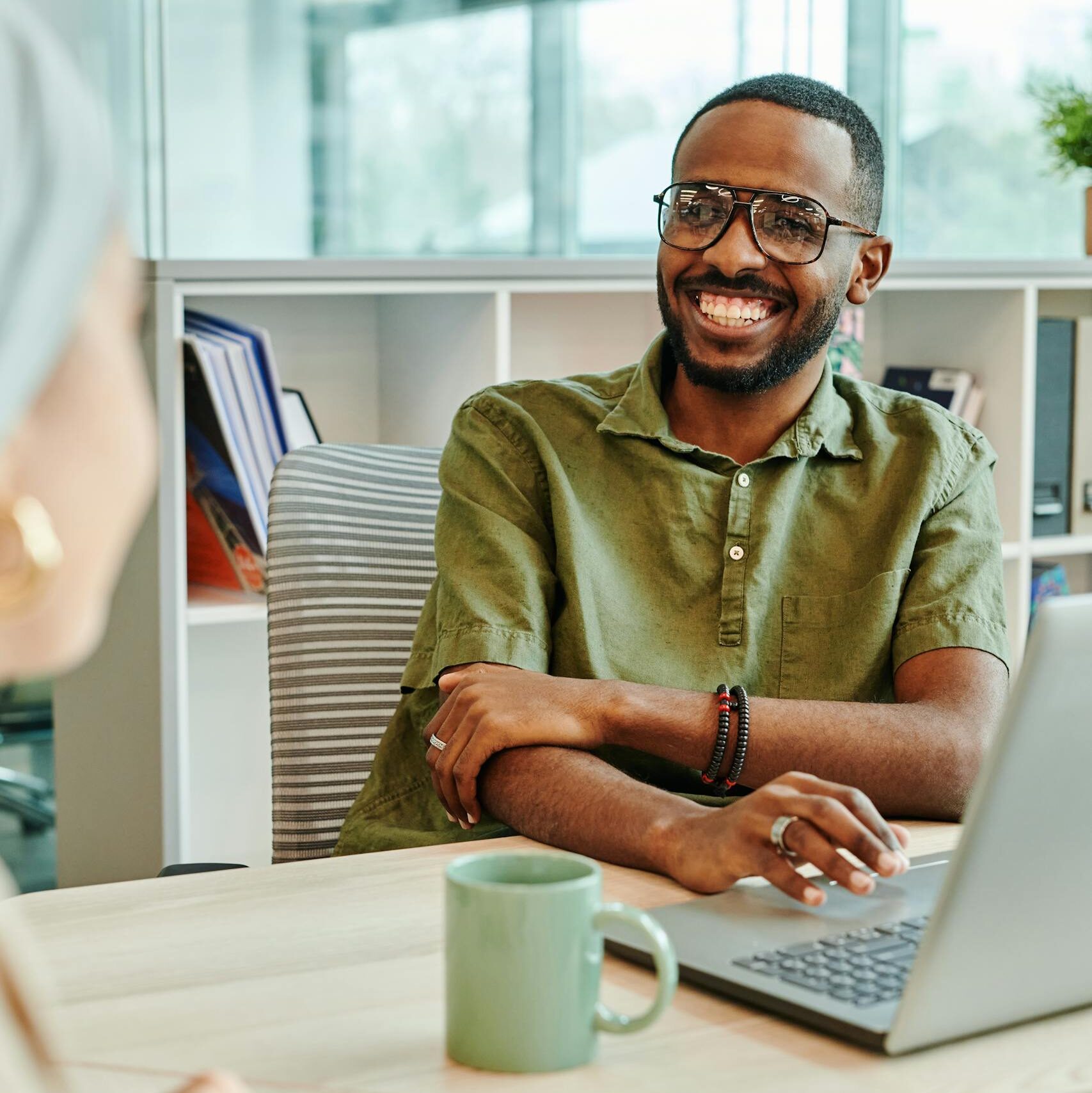 Software Engineering Core 1 Cheerful man working at a desk in a modern office with laptop and coffee mug.